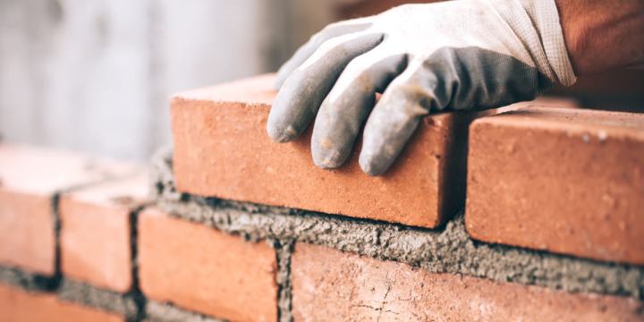 Close up of industrial bricklayer installing bricks on construction site
